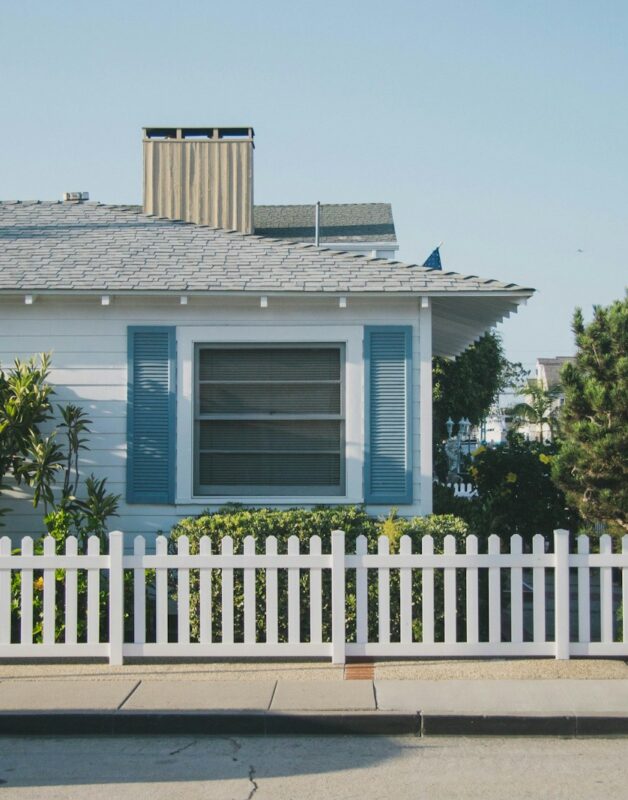 white and blue house beside fence