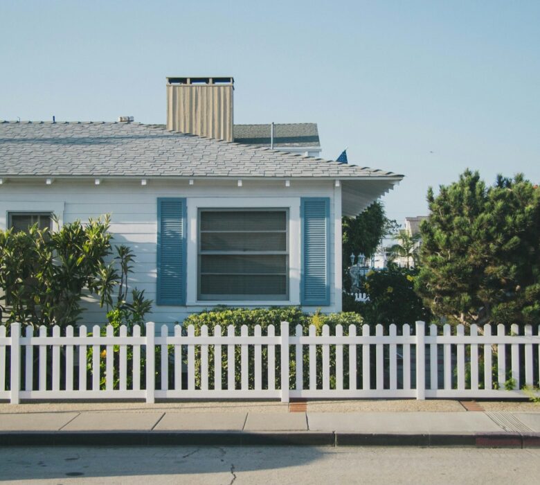 white and blue house beside fence