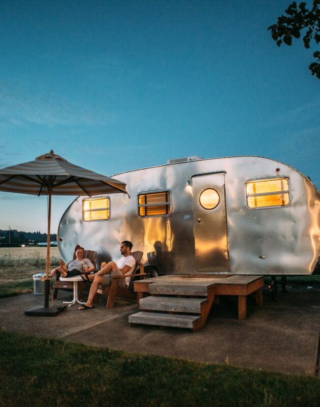 man and woman sitting in front of RV trailer