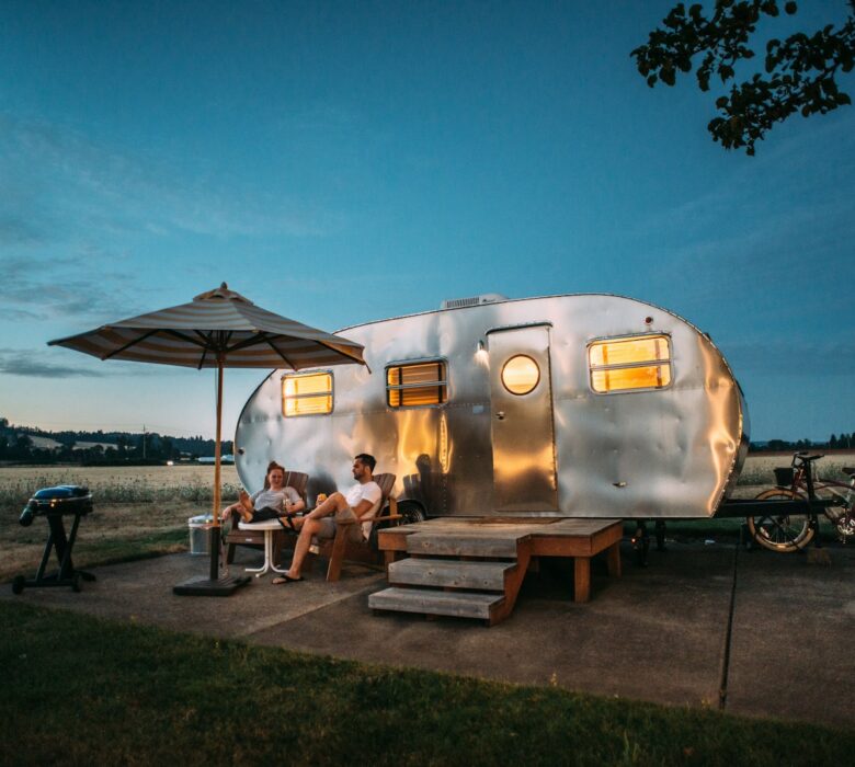 man and woman sitting in front of RV trailer